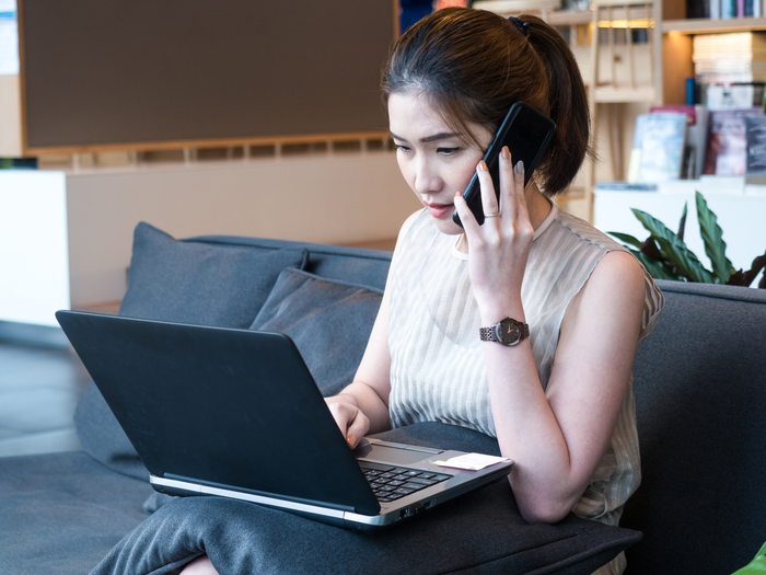 A woman taking a phone call from home while working at her laptop